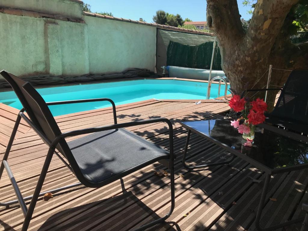 einen Stuhl auf einer Terrasse neben einem Pool in der Unterkunft Chambre climatisée avec sdb privée dans une villa avec piscine ouverte d'avril à mi octobre in Marseille