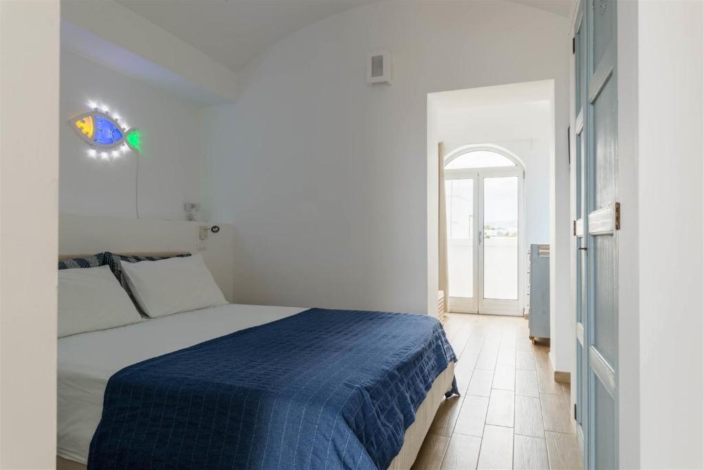 a white bedroom with a bed with a blue blanket at Casetta Mare in Villanova di Ostuni