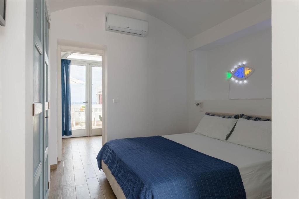a white bedroom with a bed and a window at Casetta Mare in Villanova di Ostuni