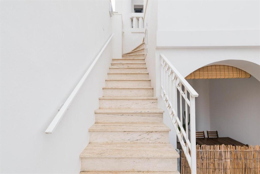 a staircase in a house with white walls and wooden floors at Casetta Mare in Villanova di Ostuni