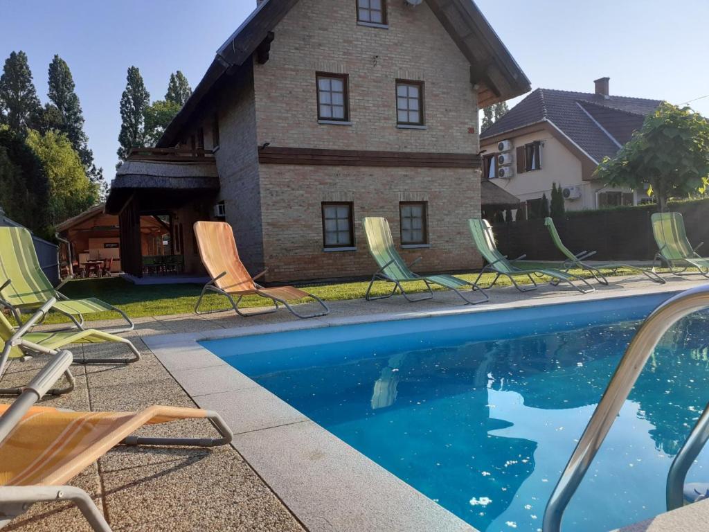 a group of lawn chairs and a swimming pool at Lisztes Apartman (medencés, nádfedeles, Zamárdi) in Zamárdi