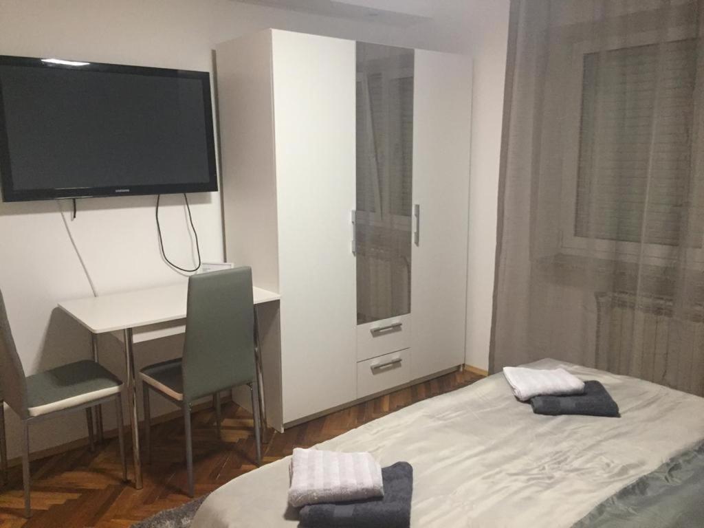 Habitación con cama, escritorio y TV. en Apartmani Anton, en Osijek