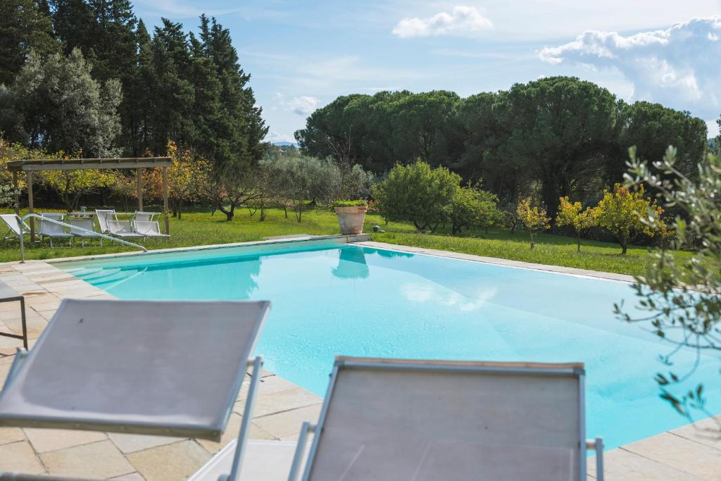 una gran piscina con 2 sillas y árboles en Fattoria Laviosa, en Fauglia