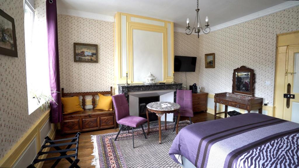 sypialnia z łóżkiem, stołem i kominkiem w obiekcie Au Chapitre w mieście Rozoy-sur-Serre