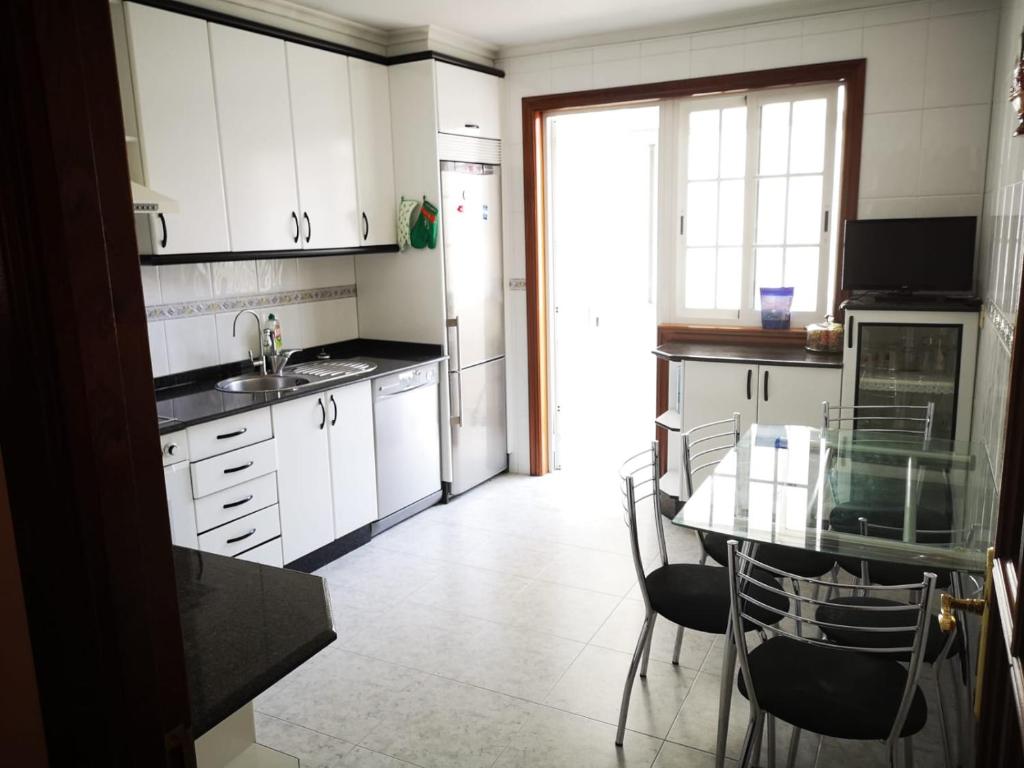eine Küche mit weißen Schränken und einem Glastisch in der Unterkunft Casa Florida® in Vigo