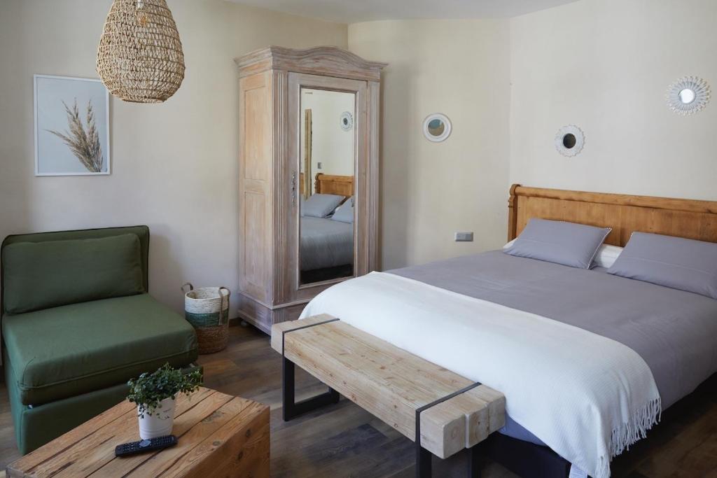 a bedroom with a bed and a chair and a mirror at Les Chambres - Au Grès du marché in La Petite-Pierre