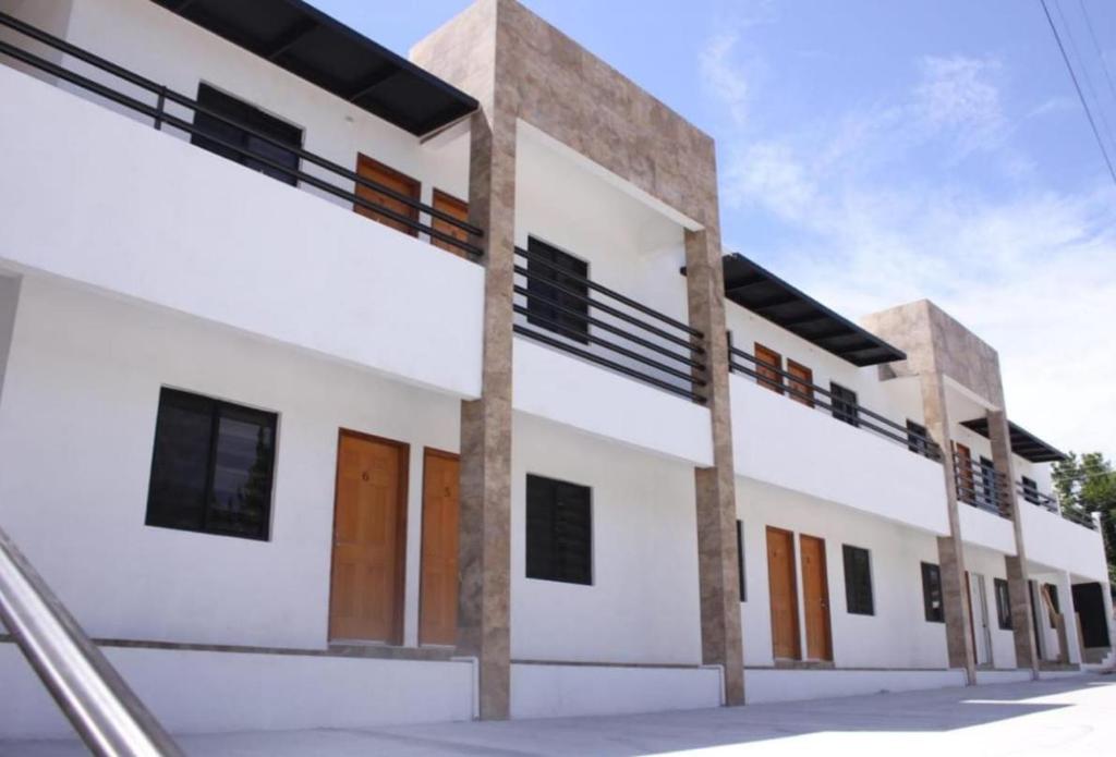 un edificio blanco con puertas y ventanas marrones en CMG Suites, en Ciudad Acuña
