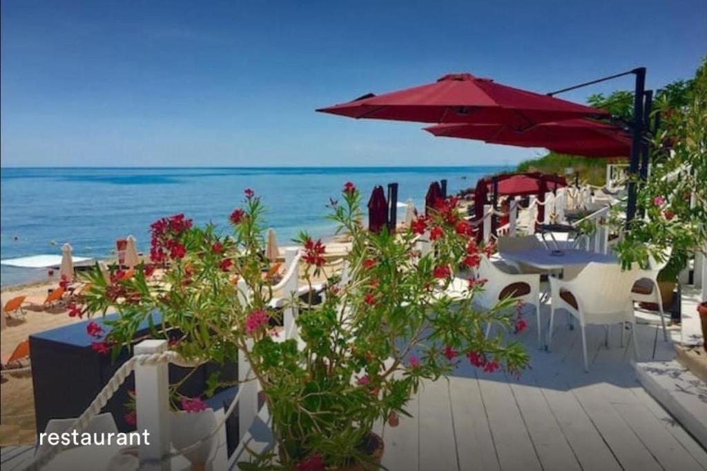 a beach with white chairs and an umbrella and the ocean at La Mer Welcome in Golden Sands