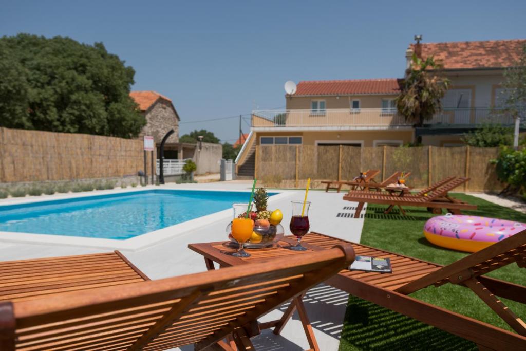 un patio trasero con una piscina y una mesa con bebidas. en Apartments Brkić en Lozovac