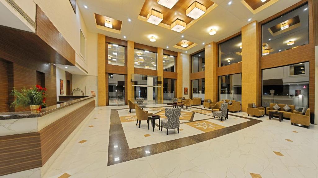 a lobby with tables and chairs in a building at Poppys Hotel Madurai in Madurai