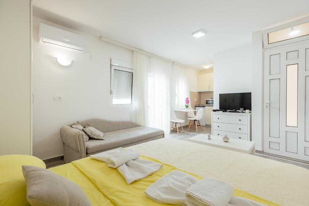 ein Schlafzimmer mit einem gelben Bett und einem Sofa in der Unterkunft Todorovic apartmani in Herceg-Novi