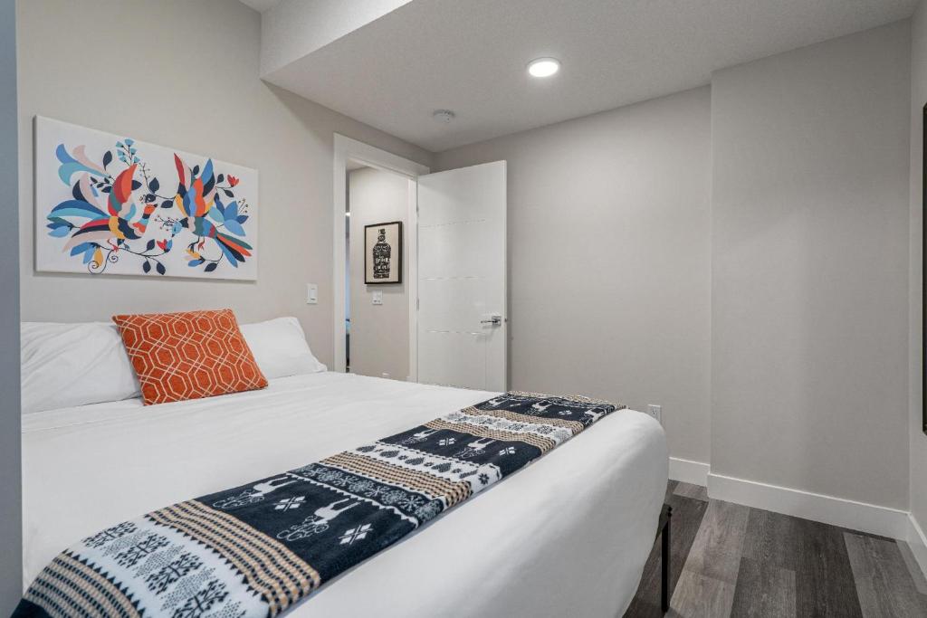 a bedroom with a white bed with an orange pillow at Contemporary 1br Home Full Kitchen Smarttv in Calgary