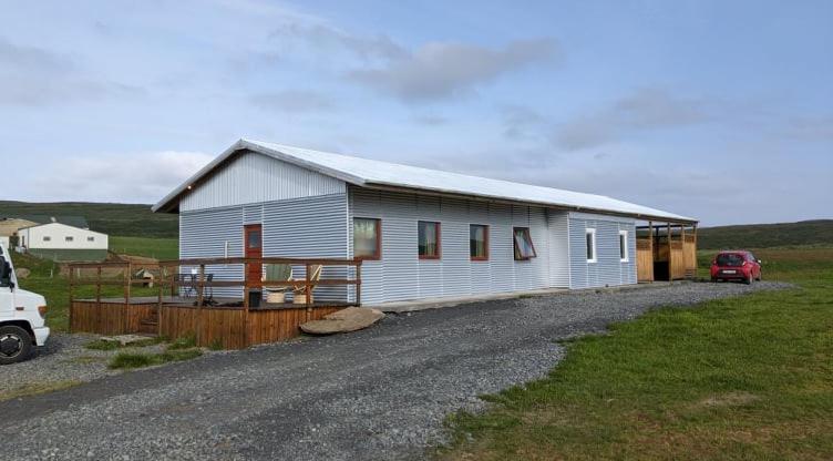 um celeiro com um carro estacionado em frente dele em Bjarnastaðir Guesthouse em Kópasker