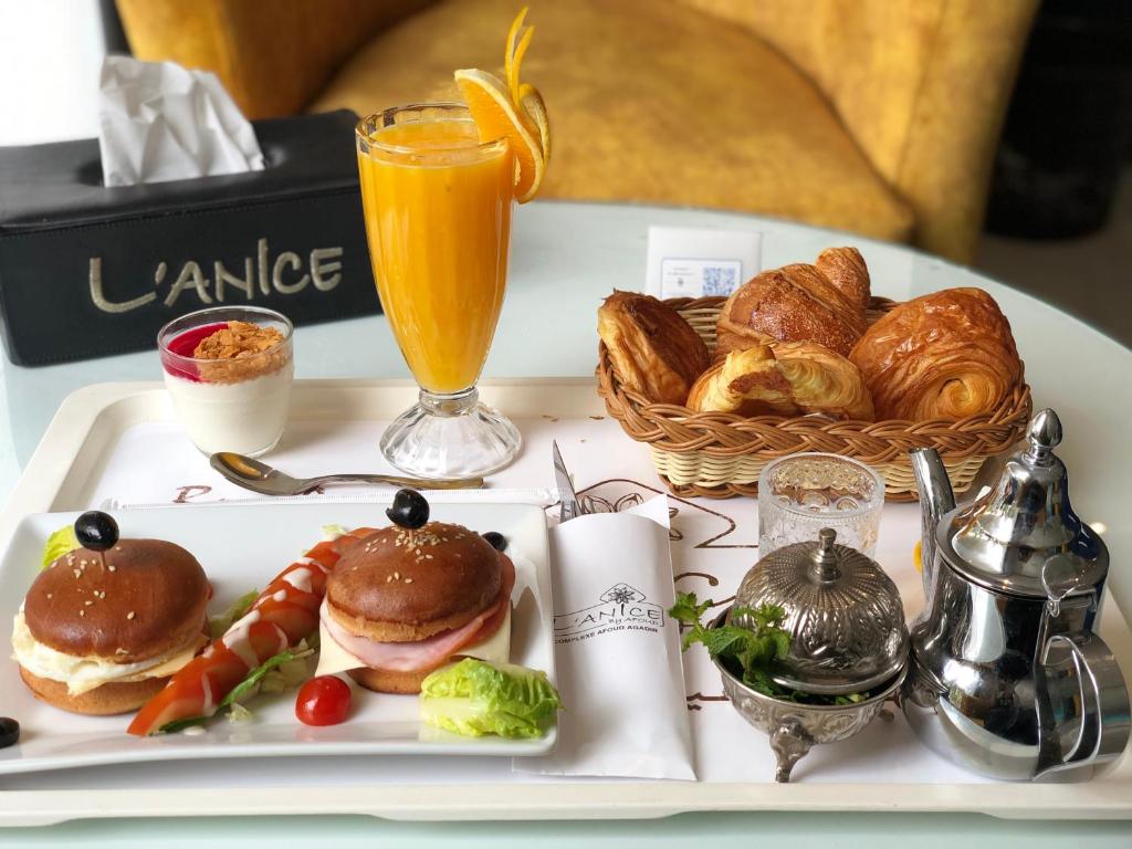 a tray of food with sandwiches and croissants and a drink at Studiotel Afoud in Agadir