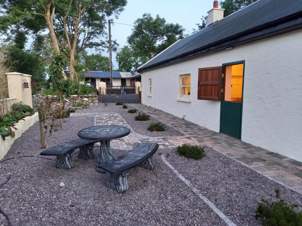 una mesa y dos bancos frente a un edificio en Mary's Bespoke Cottage, en Killarney