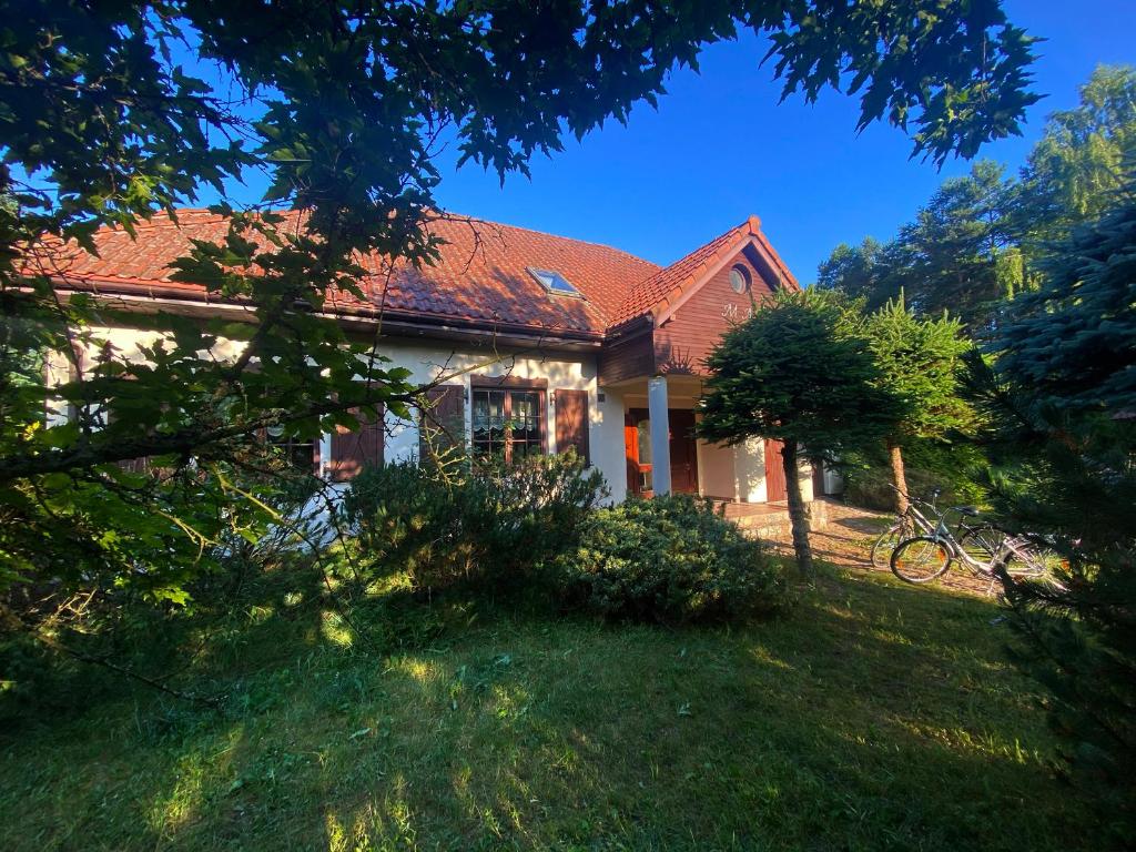 dom z czerwonym dachem na dziedzińcu w obiekcie Szeroki Bór oaza w Puszczy z Sauną, Banią i Jacuzzi w mieście Szeroki Bór