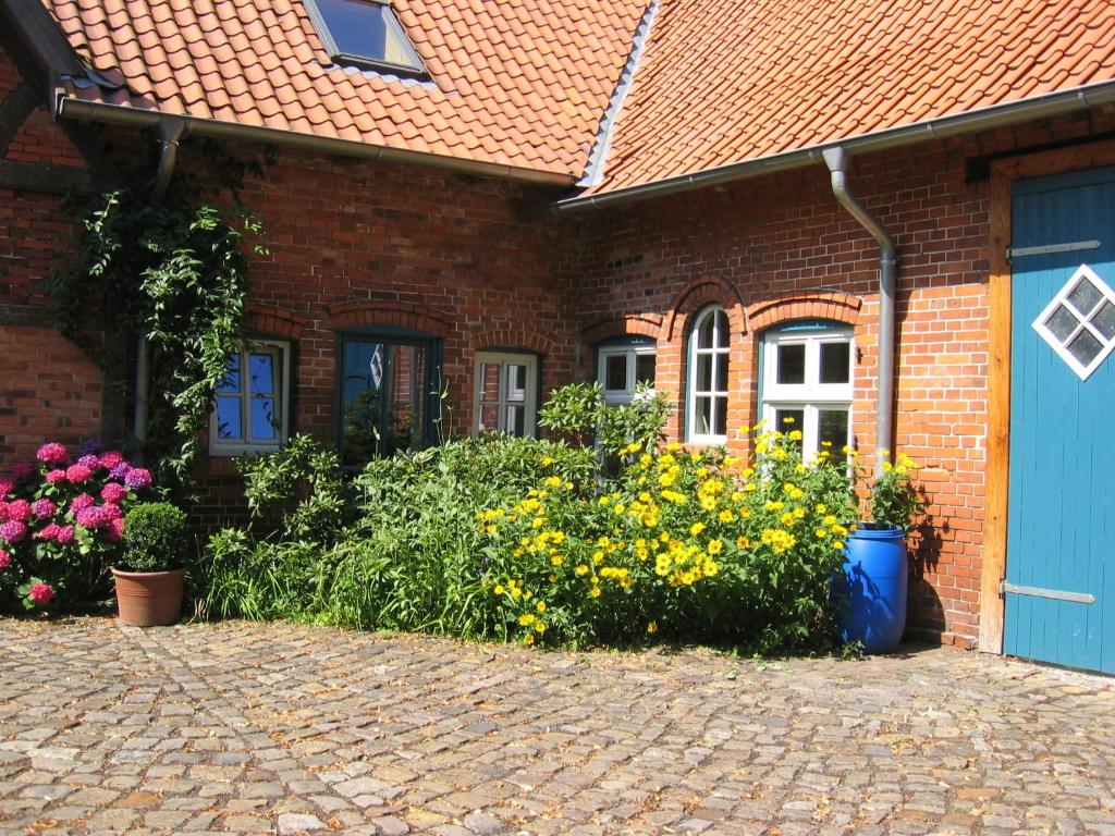 a brick house with a blue door and some flowers at Bio Ferienwohnung in Dörverden