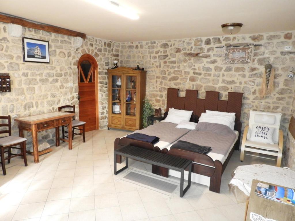 a bedroom with two beds in a room with stone walls at Zupan B studio apartman Krk in Krk