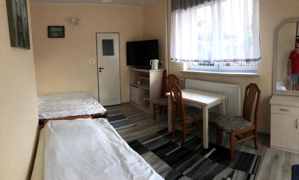 ブワディスワボボにあるPokoje Gościnne Szymonのベッド、テーブル、椅子が備わる小さな客室です。