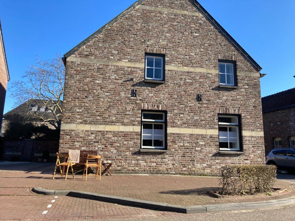 een bakstenen gebouw met een tafel en stoelen ervoor bij Huize Bronsgroen - vakantiehuis voor 2-6 pers in Limburgse Heuvelland in Cadier en Keer