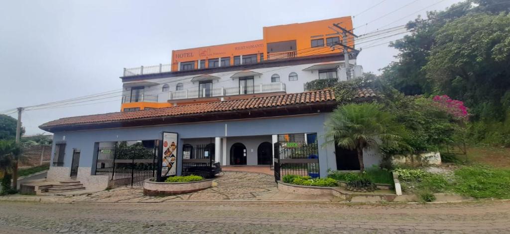 ein großes weißes Gebäude mit orangefarbenem Dach in der Unterkunft Vista Los Volcanes Hotel y Restaurante in Juayúa