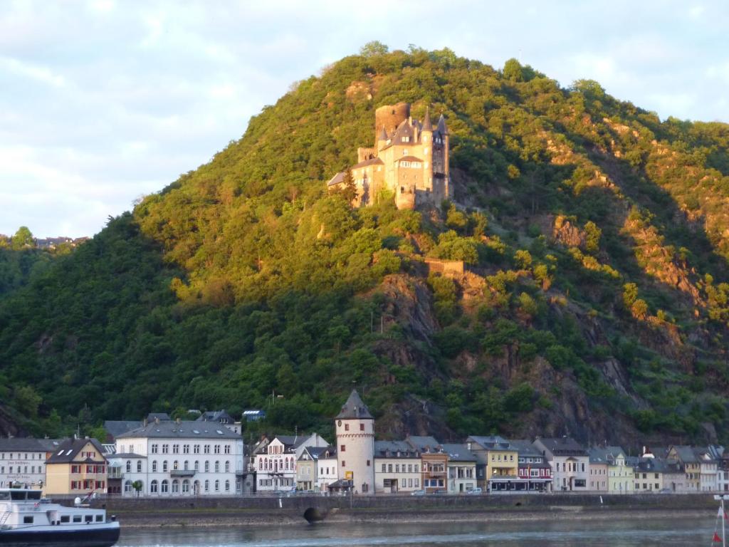 eine Burg auf einem Hügel neben dem Wasser in der Unterkunft Hotel am Markt Sankt Goar in Sankt Goar