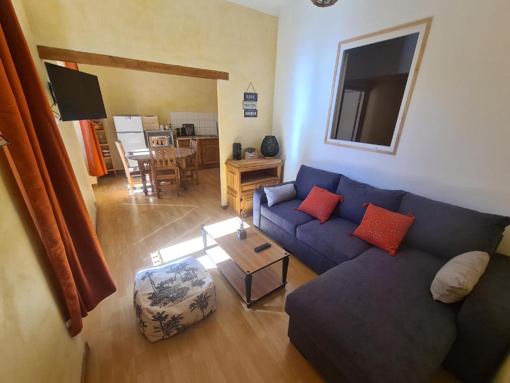 uma sala de estar com um sofá azul e uma mesa em Appart plein centre lit King size et canapé lit em Barcelonnette