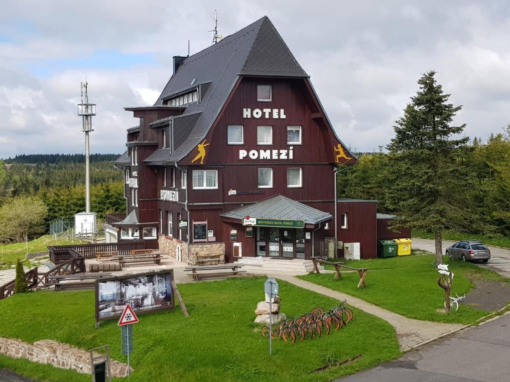 Hotel a restaurace Pomezí في Cínovec: مبنى بني كبير مع علامة تقرأ بوابة الفندق