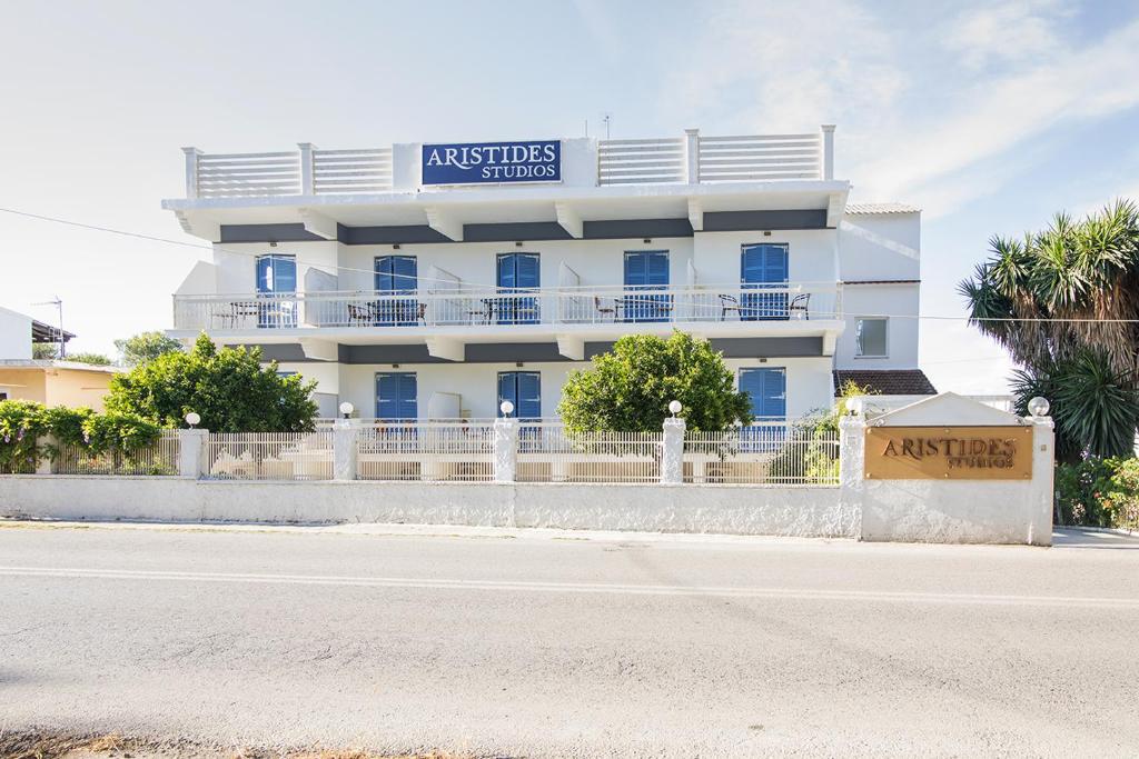 a white building with a sign on top of it at Aristides Studios in Perama