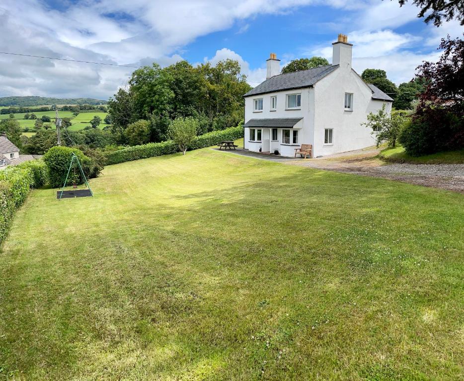 une maison blanche avec une grande pelouse dans l'établissement Garth- Stunning Scenic semi-rural Cottage with Games room, à Conwy
