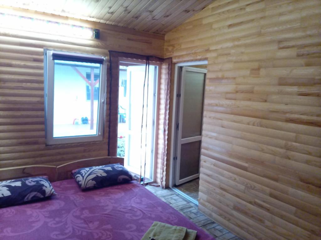 a bedroom with wooden walls and a bed with pillows at Pansionat Fortuna in Lebedevka