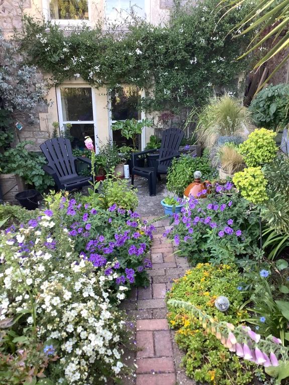 einen Garten mit zwei Stühlen und ein paar Blumen in der Unterkunft Garden apartment in Weston-super-Mare