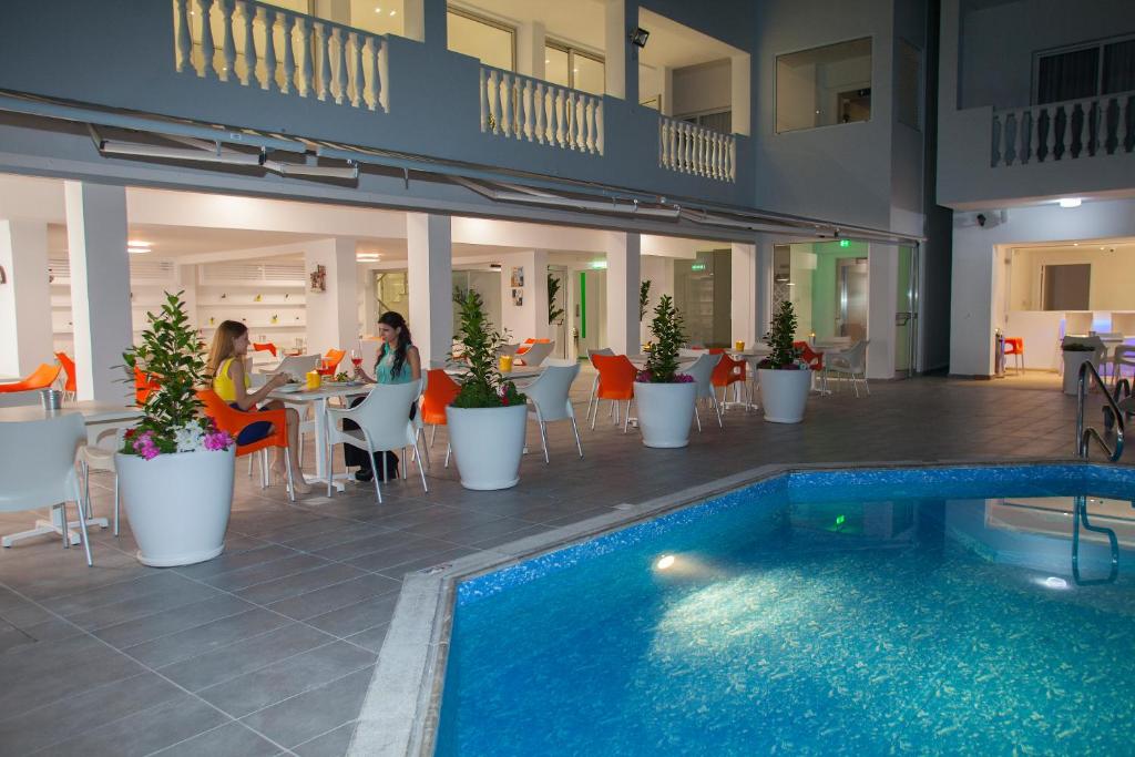a hotel with a swimming pool and people sitting at a restaurant at Princessa Vera Hotel Apartments in Paphos