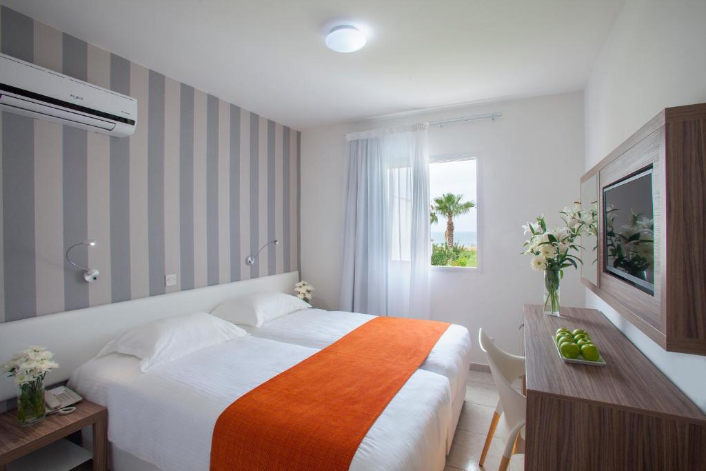 a bedroom with a bed and a desk and a window at Princessa Vera Hotel Apartments in Paphos