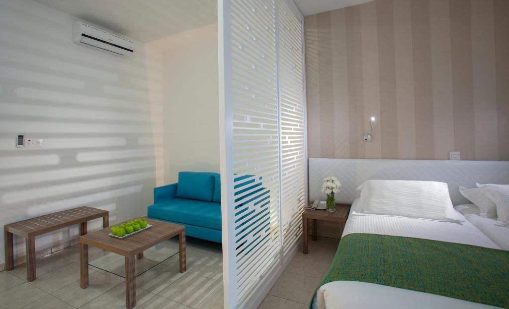 a hotel room with a bed and a blue chair at Princessa Vera Hotel Apartments in Paphos