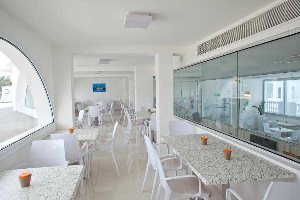a restaurant with white tables and white chairs at Princessa Vera Hotel Apartments in Paphos