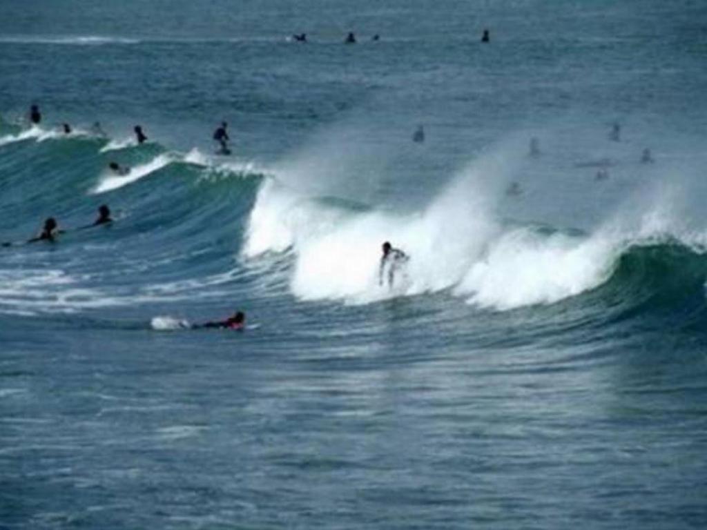 a group of people riding a wave in the ocean at Apartment by the Beach Praia da Areia Branca in Lourinhã