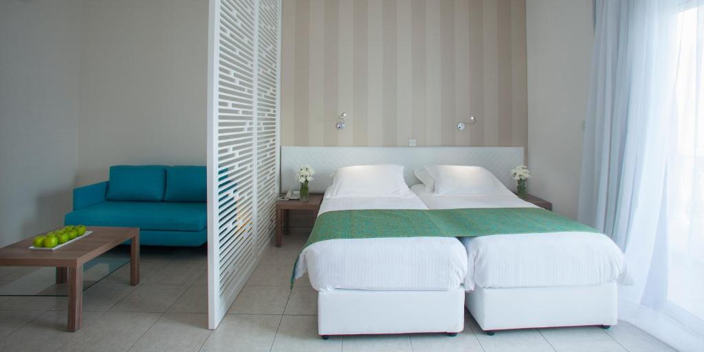 a bedroom with two beds and a blue chair at Princessa Vera Hotel Apartments in Paphos