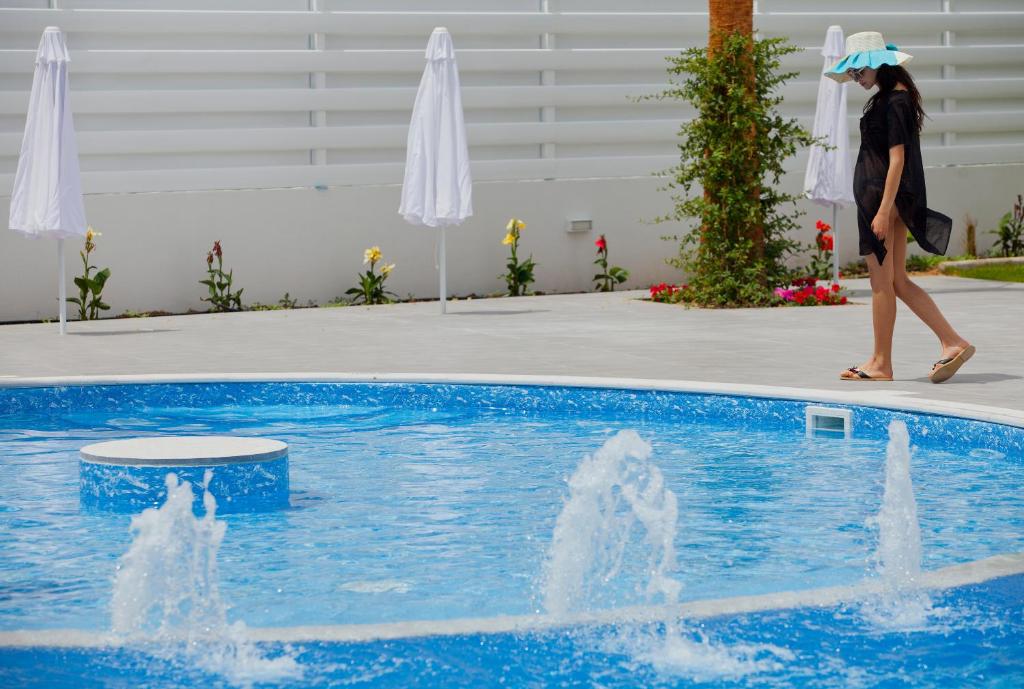 a woman with an umbrella walking by a swimming pool at Princessa Vera Hotel Apartments in Paphos