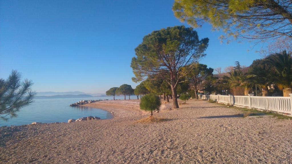 a beach with trees and a fence and the water at Apartments Fina in Crikvenica
