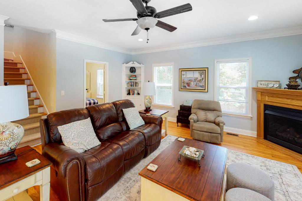a living room with a leather couch and a fireplace at Chateau Relaxo in Edisto Beach