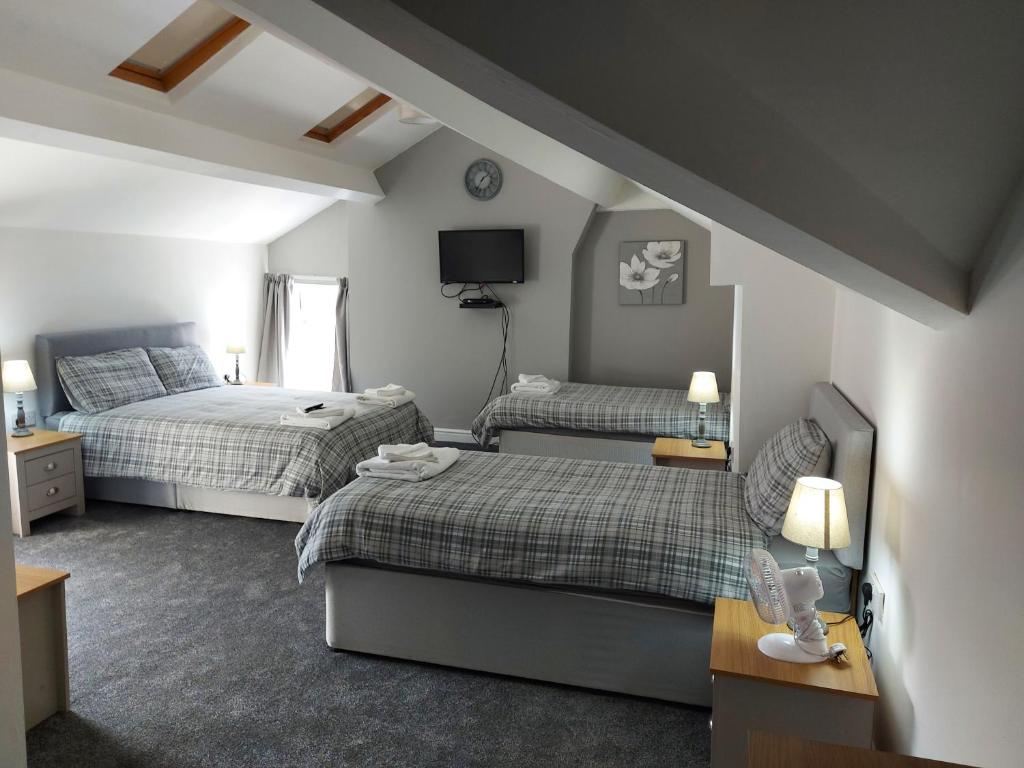 a small bedroom with two beds and a tv at Ambrose Hotel in Barrow in Furness