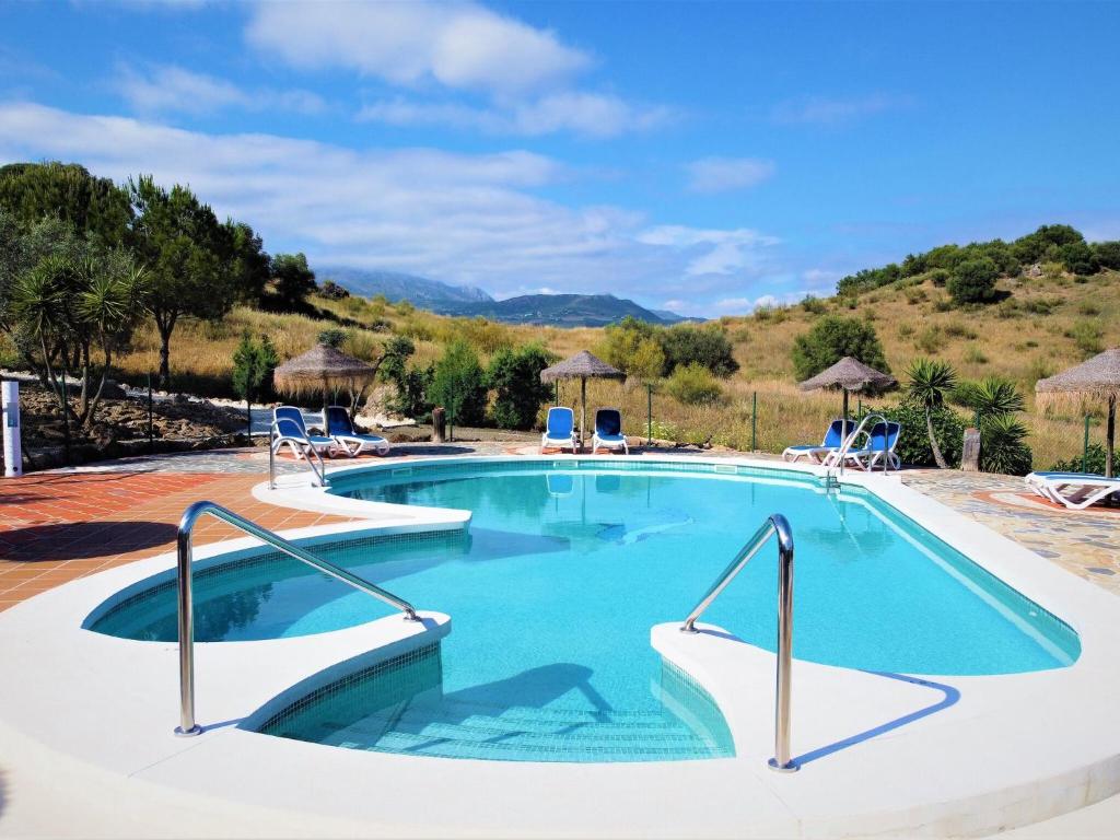 a large swimming pool with chairs and umbrellas at Belvilla by OYO Casas Rurales Huetor in Viñuela