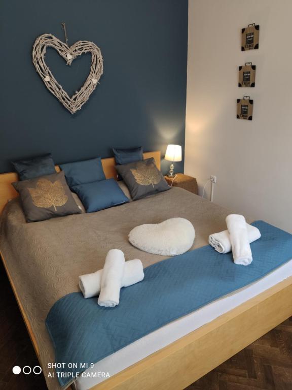 a bed with white pillows and a heart on the wall at Bíborlak 6 in Villány