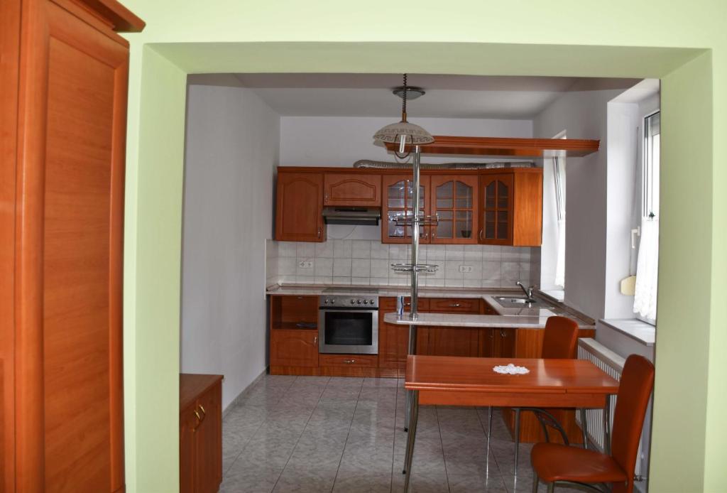 cocina con armarios de madera, mesa y comedor en Pilikán Apartments Lenti, en Lenti
