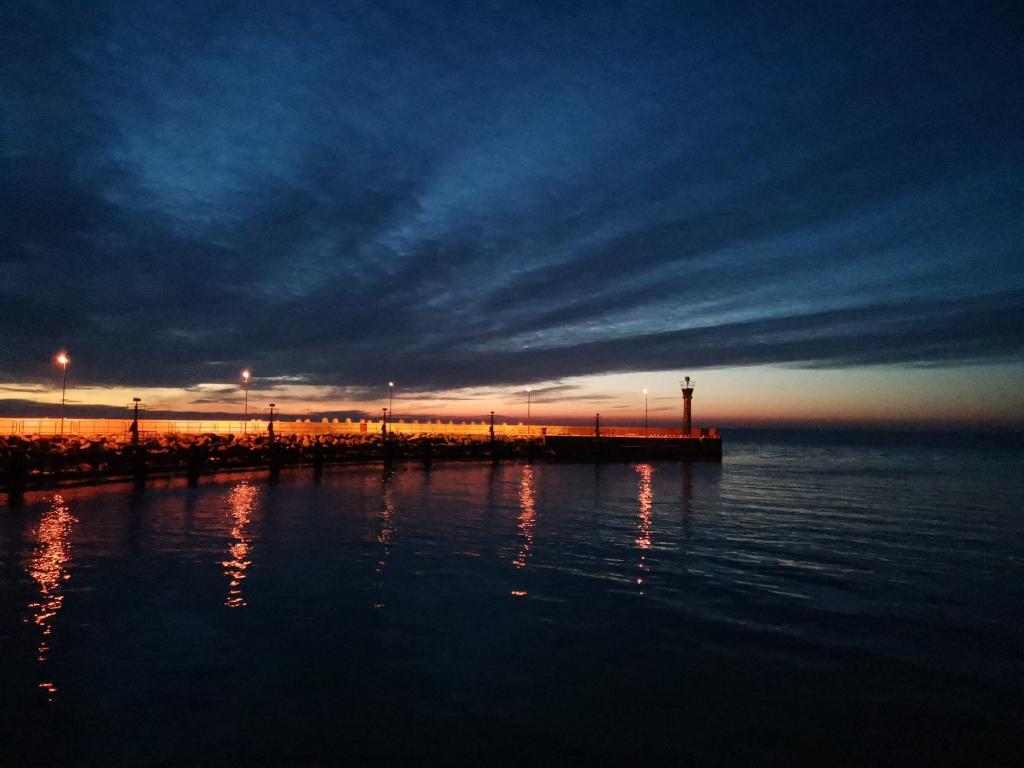 a pier in the middle of the water at sunset at Goose Home and Garden in Łeba