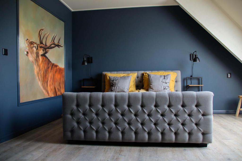 una sala de estar con sofá y una pintura de un ciervo. en B&B Schotererf, en Kuinre