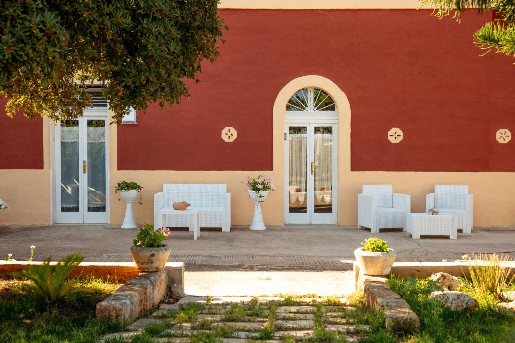 a building with white chairs and a red wall at Dimora dei nonni 199 in Monopoli