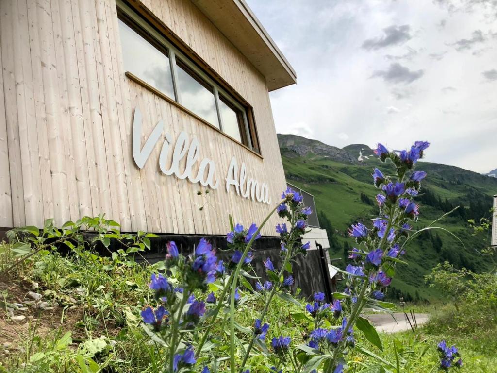 un bâtiment avec des fleurs violettes devant lui dans l'établissement Villa Alma Arlberg, à Warth am Arlberg