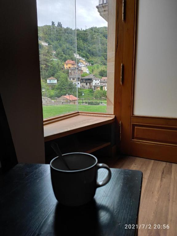 una taza de café sentada en una mesa frente a una ventana en Prao del Molin en Cangas del Narcea